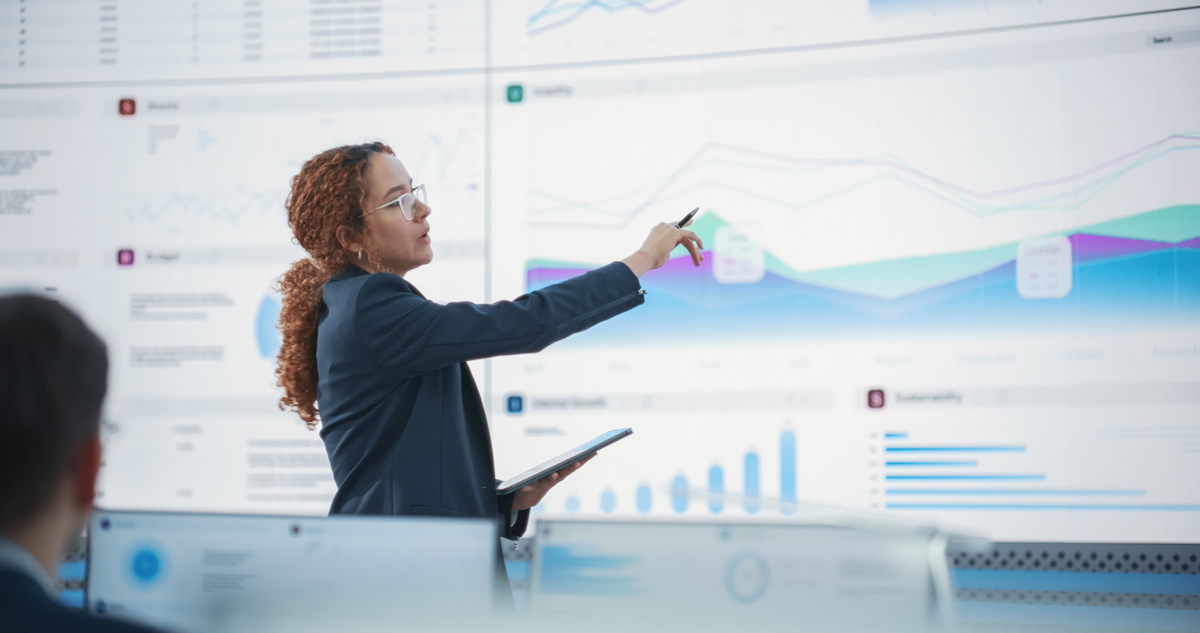 Analyst presenting operating and financial trends on a large display.